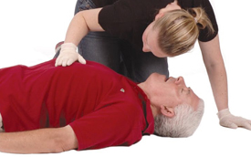 Woman placing her hand on a patient’s chest and placing her cheek over man’s mouth to check for signs of man breathing.
